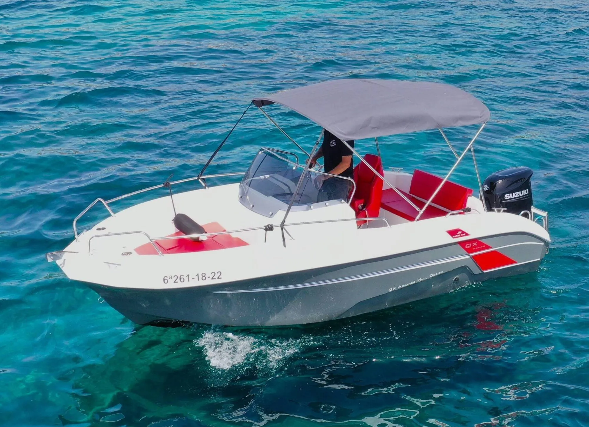 Marine Time 562, a white and grey motorboat with red seats and a bimini top, on turquoise water