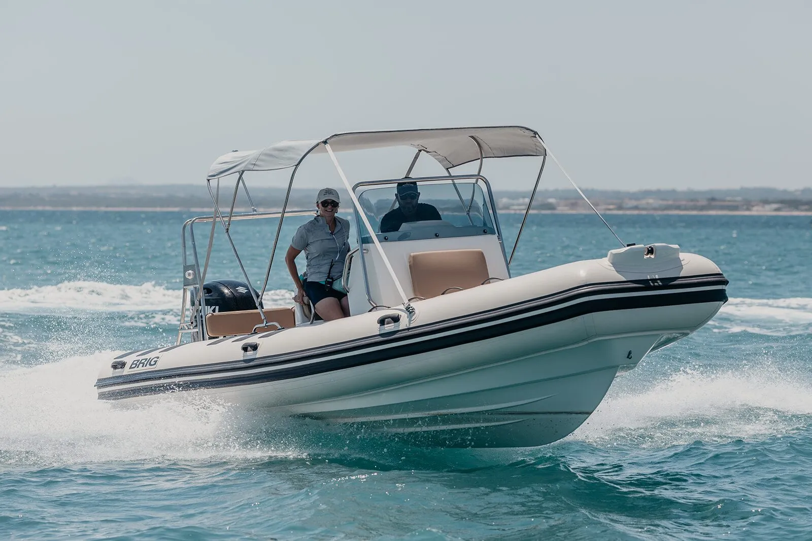 BRIG 700, a white rigid inflatable boat with a bimini top, cruising at speed