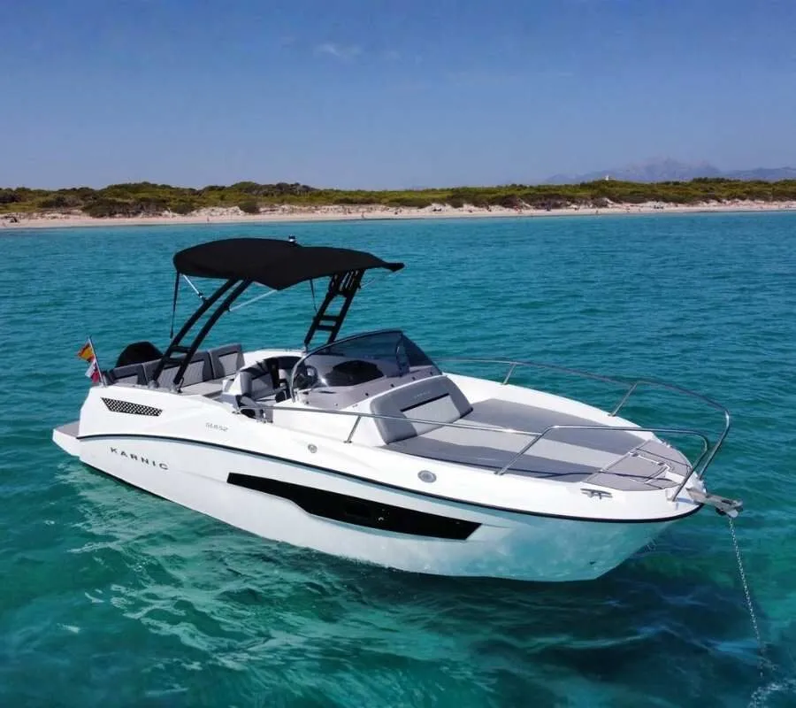 Karnic 650, a white motorboat with a black tower and bimini, at anchor on turquoise water