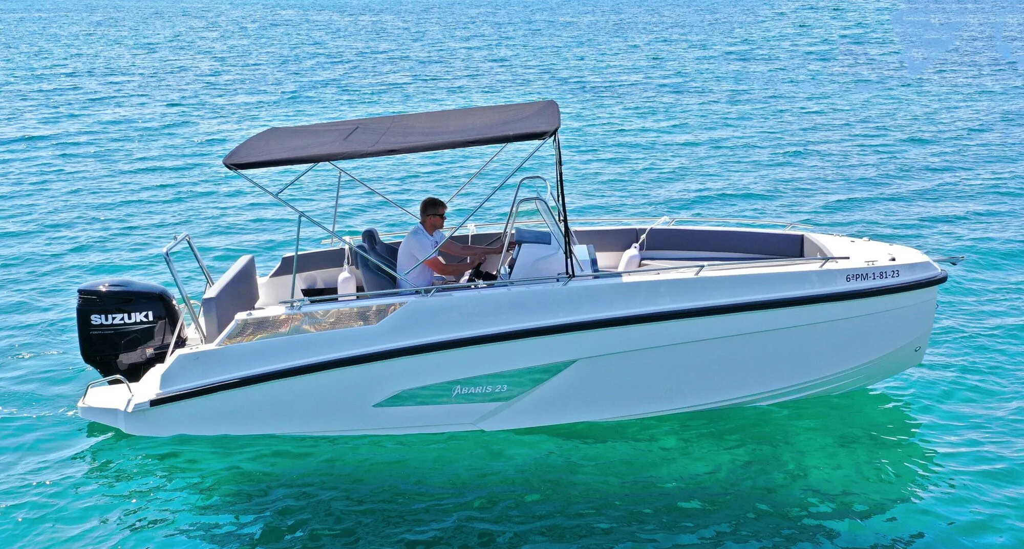 Abaris 23, a white open motorboat with a black bimini top, on turquoise water