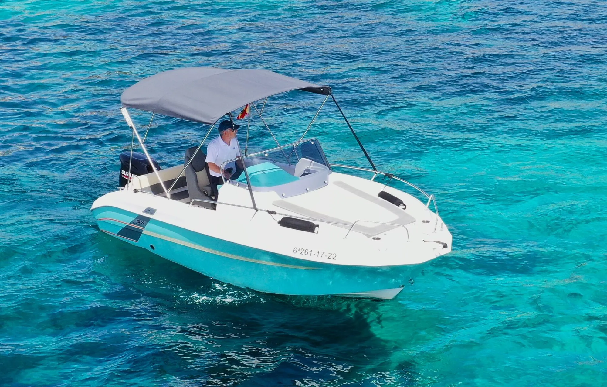 Marine Time 563, a white and light blue motorboat with a bimini top, on turquoise water