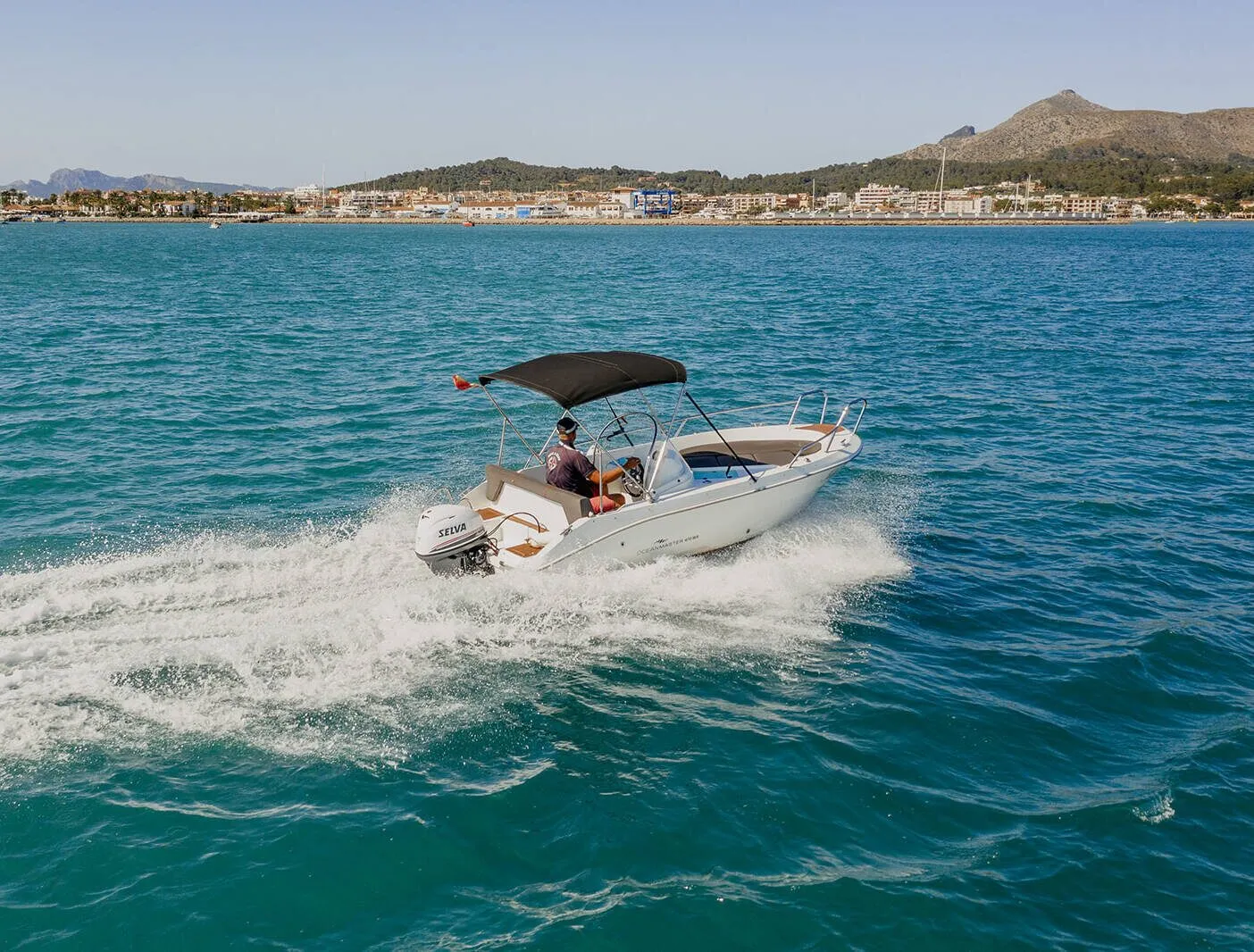 Ocean Master underway and leaving a wake, with the coast behind