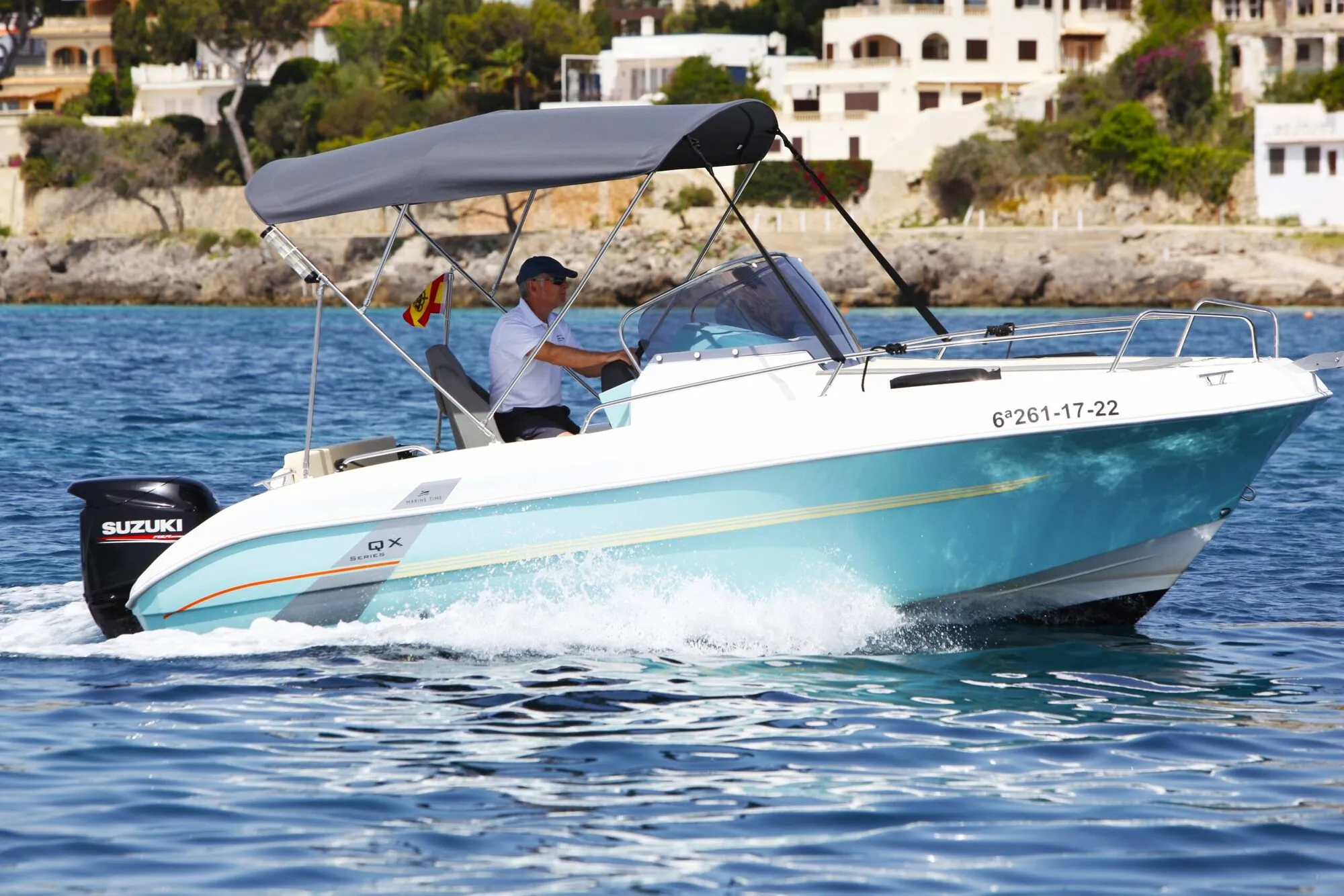 Marine Time 563 cruising past a rocky shore with white villas