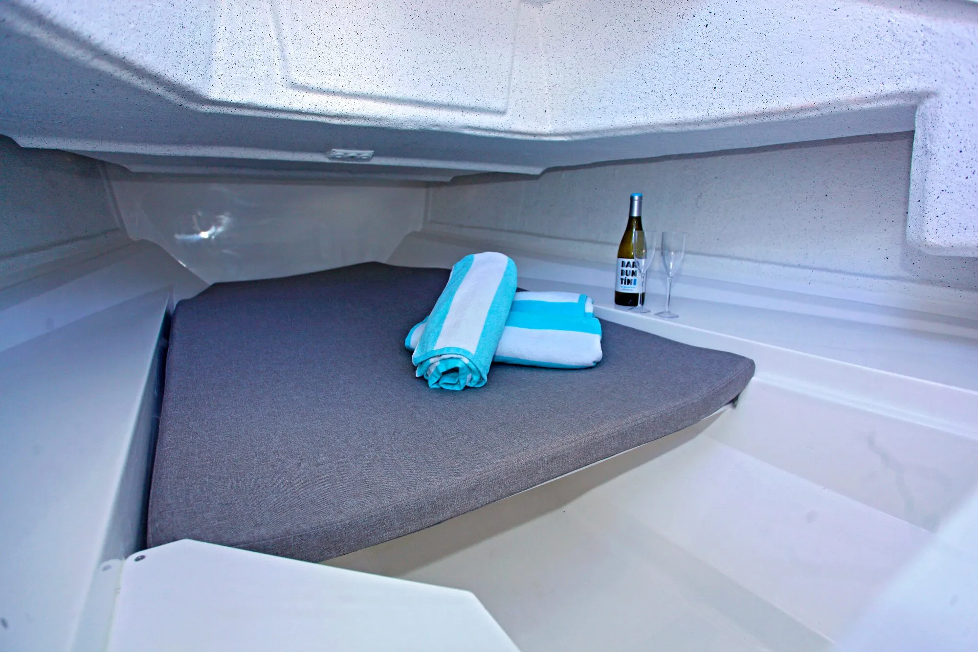 Cabin berth of the Abaris 23 with towels and a bottle of wine