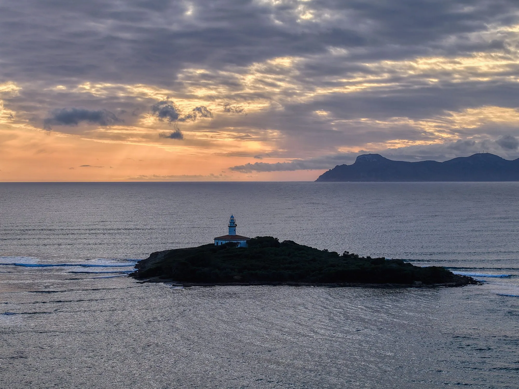 Small island with a lighthouse in a calm bay