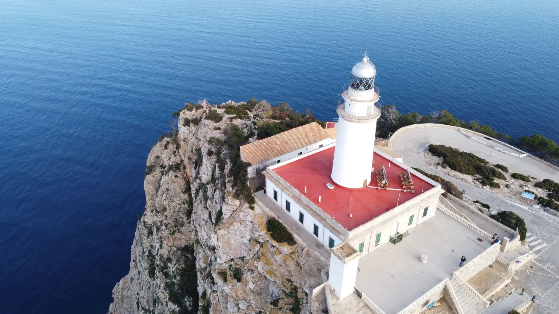 The white Formentor lighthouse on the edge of the cliff, seen from above